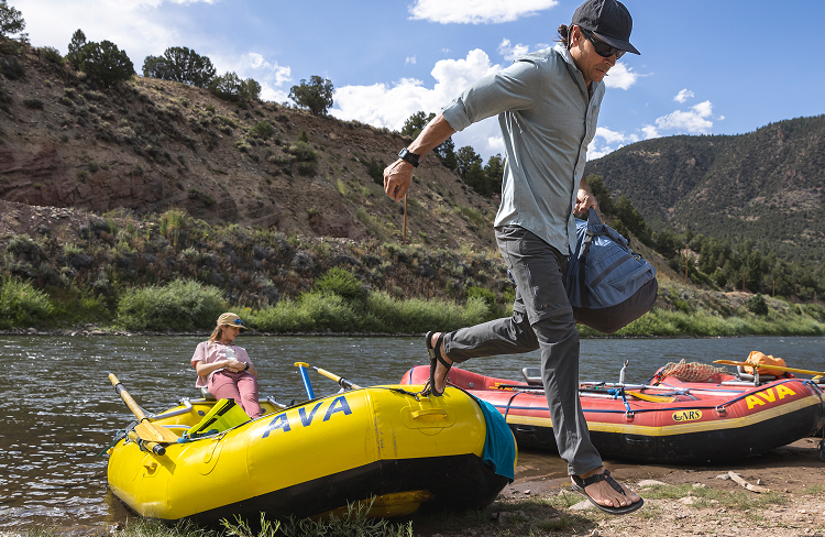 Man jumping out of raft holding a bag