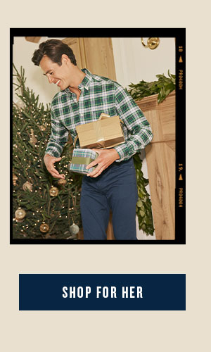 Man in green plaid sport shirt and navy pants holding Christmas gifts. Shop for Her.