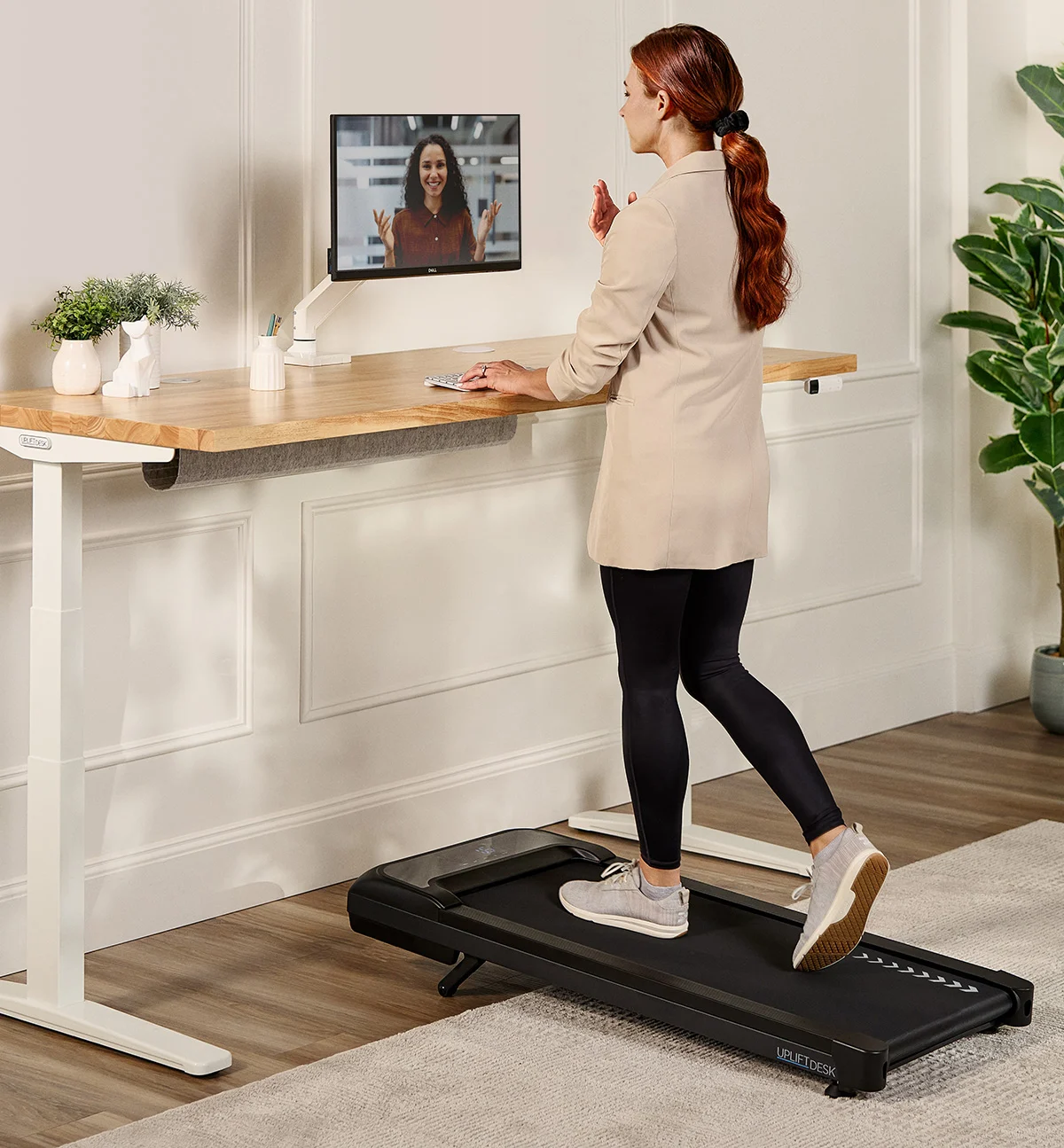 A woman walking on an inclining walking pad while at her desk