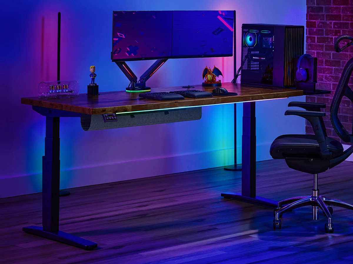 A gaming setup lit with RGB lights on an UPLIFT V3 Standing Desk