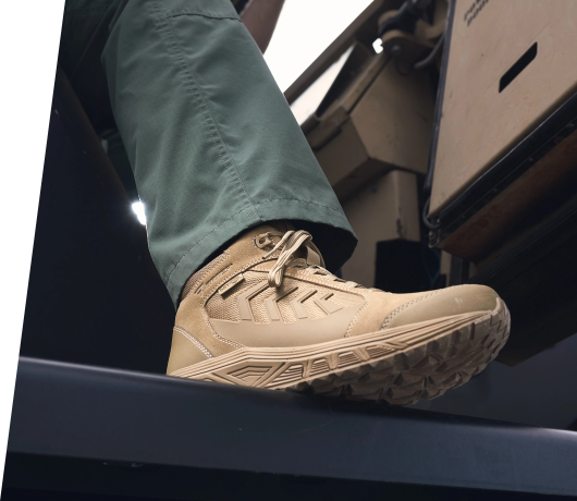 Image focusing on a tan tactical boot worn by someone stepping on the ledge of a vehicle