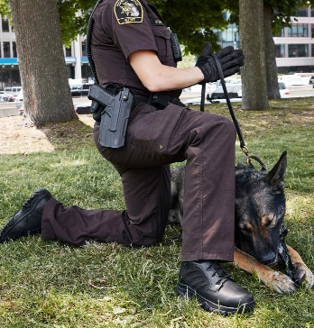 Uniformed police officer kneeling by their dog