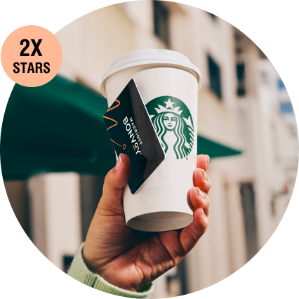 A closeup of someone holding a Marriott Bonvoy key card and Starbucks beverage.