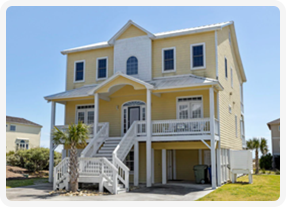 Yellow beach house with raised foundation, white trim, and front stairs leading to porch.