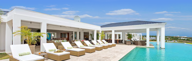 Modern luxury villa with a long resort‑style pool, sun loungers, and open outdoor living areas.