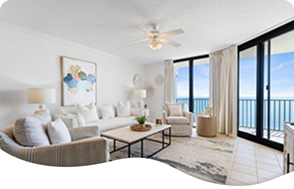 Bright coastal living room with white décor and floor‑to‑ceiling windows facing the ocean.