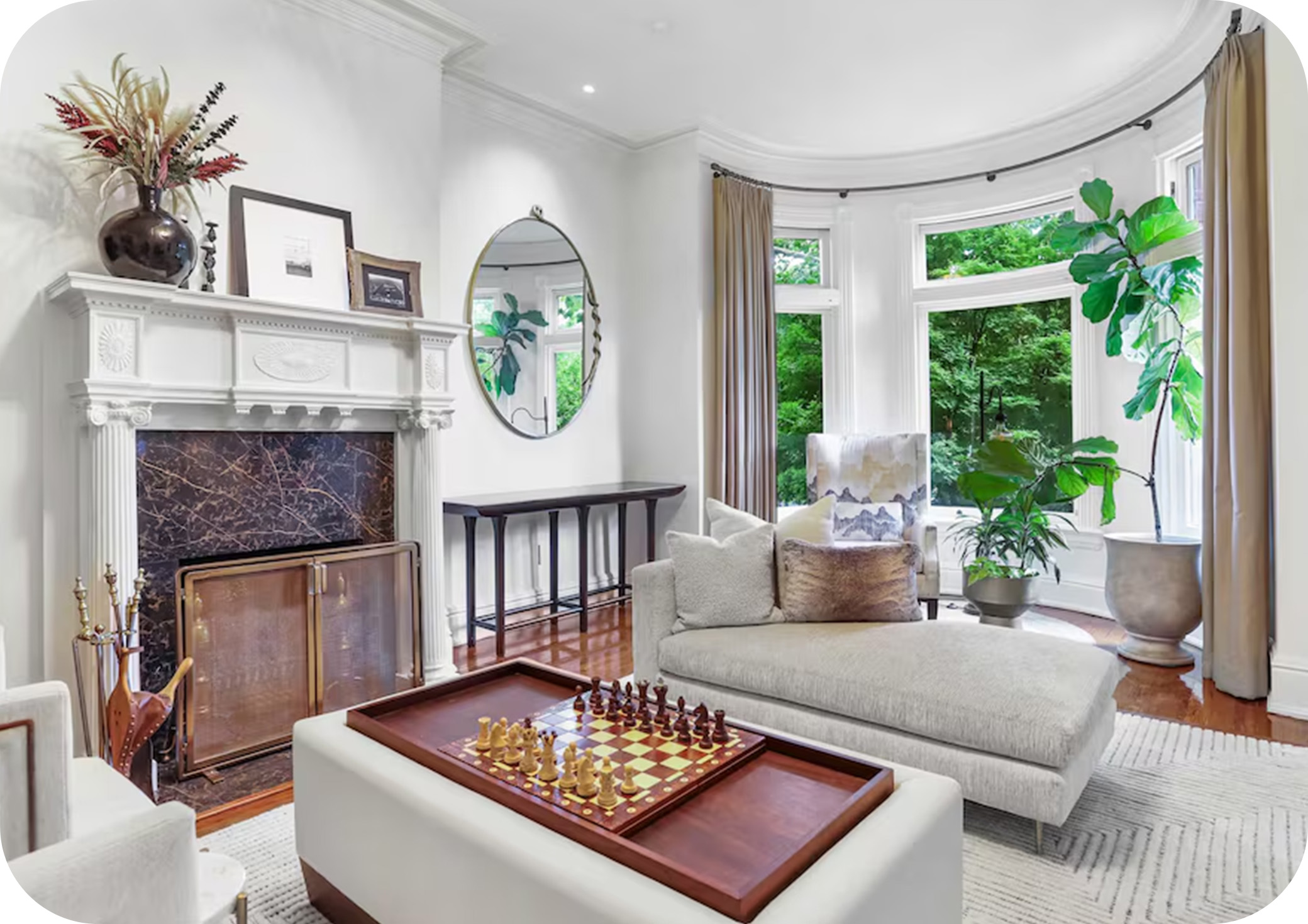 Bright living room with tall windows, a fireplace, and elegant neutral furnishings.