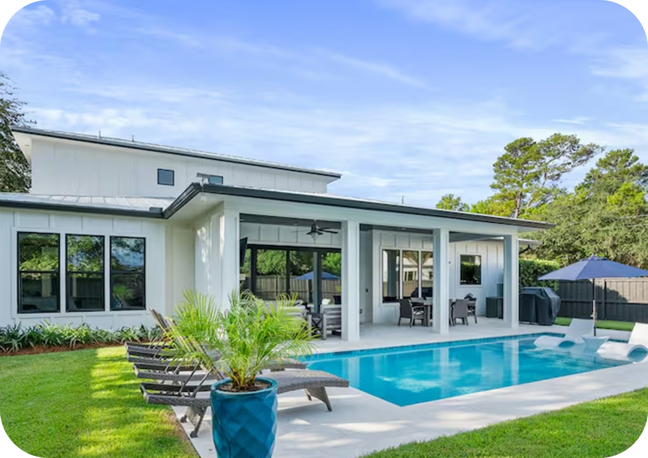 Modern home with large windows opening to a backyard pool and outdoor seating area.