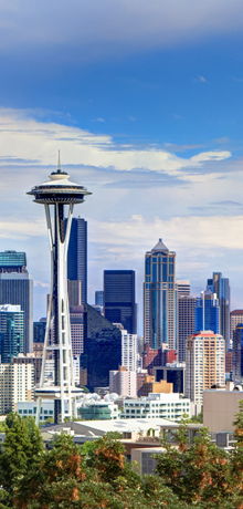 Seattle’s Space Needle rises above the downtown skyline under a blue sky.