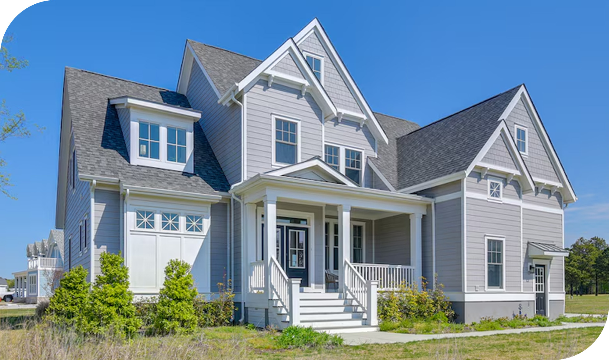 Light gray coastal-style home with gabled roof, front porch, and landscaped yard.