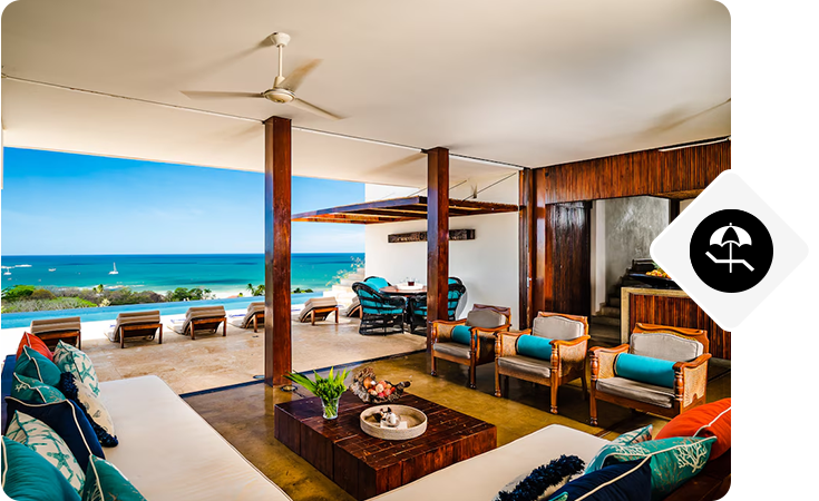 Open-air living area with wood pillars, lounge seating, and an ocean view beyond an infinity pool.
