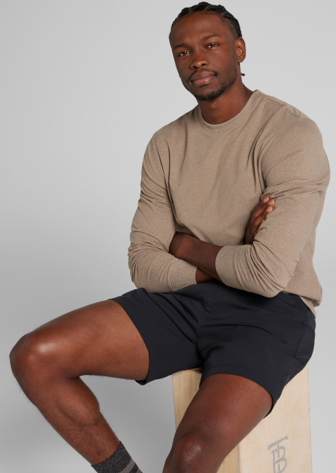 man wearing a beige long-sleeve shirt with black shorts