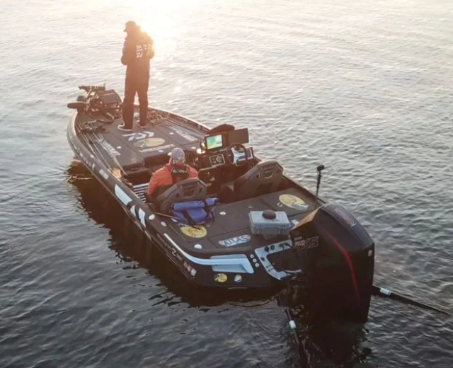 A man stands on the back of a fishing boat with a sticker on the side that says texas