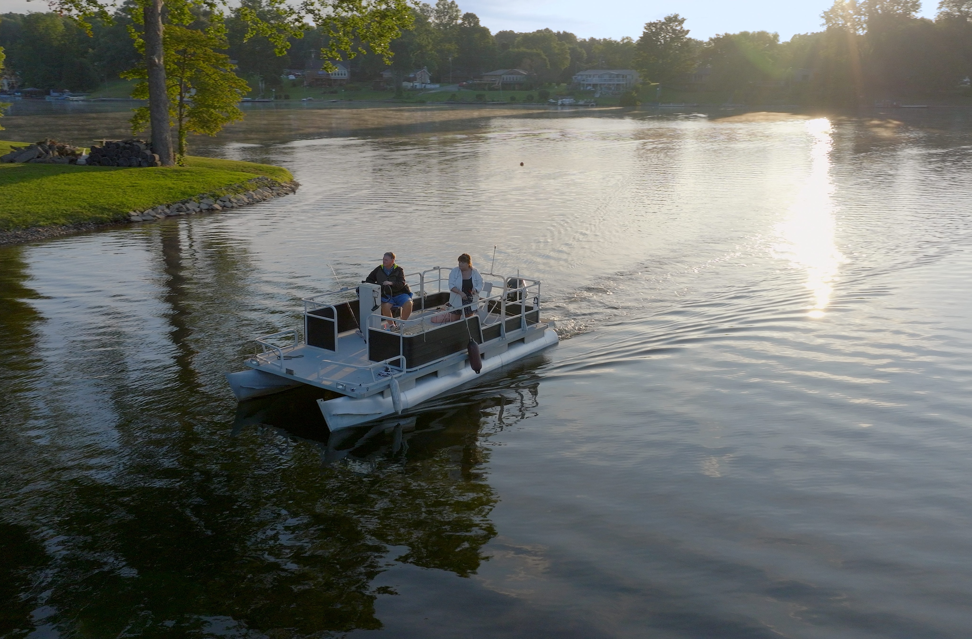 A man and a woman enjoy a peaceful morning on a pontoon boat.