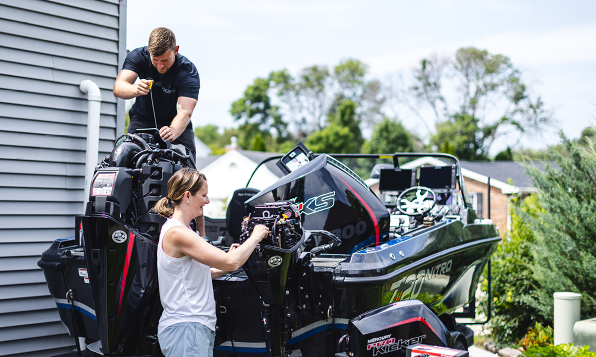 A man and a woman work on the engine of a Nitro Z20 bass boat.