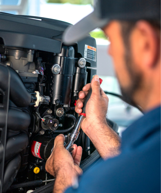 A person working on a boat engine with a wrench.