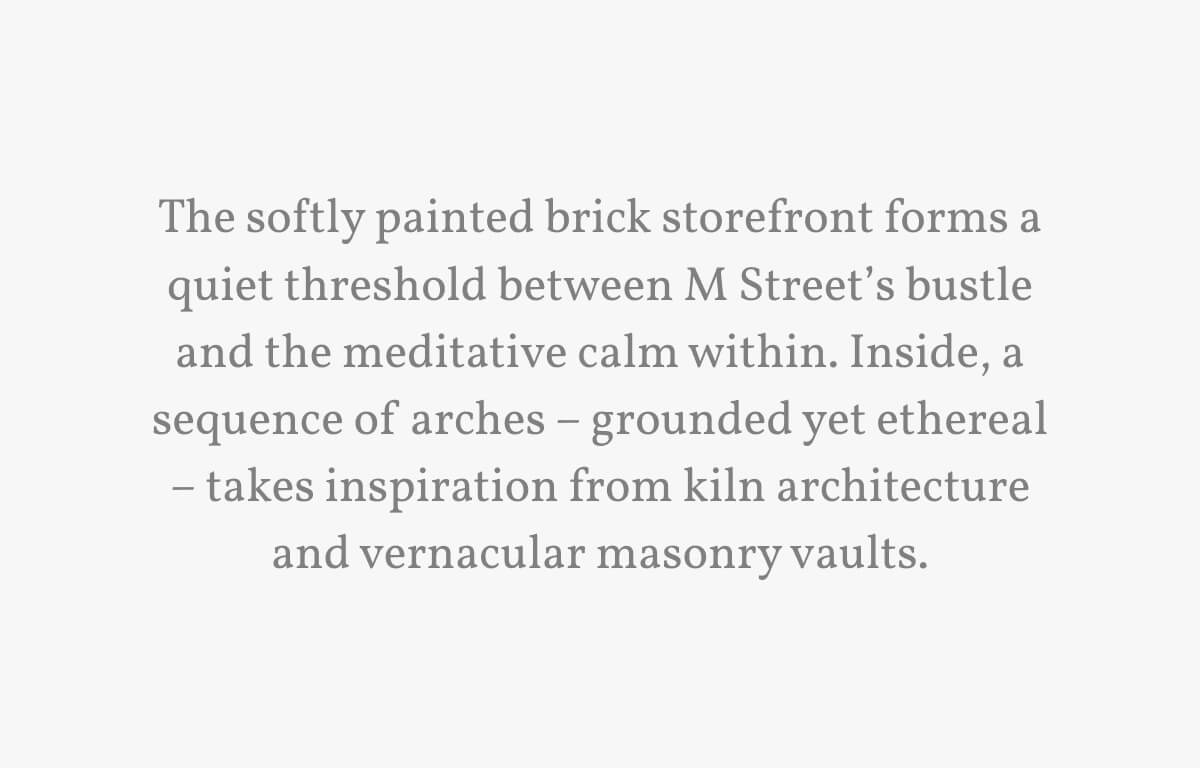 The softly painted brick storefront forms a quiet threshold between M Street’s bustle and the meditative calm within. Inside, a sequence of arches – grounded yet ethereal – takes inspiration from kiln architecture and vernacular masonry vaults.