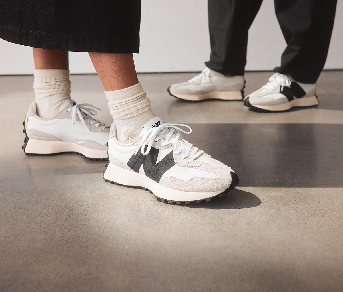 A stack of New Balance shoe boxes next to a shopping bag against a pale apricot backdrop