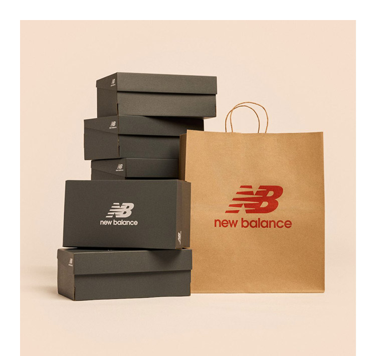 Stack of gray New Balance shoe boxes next to a shopping bag with an apricot background.
