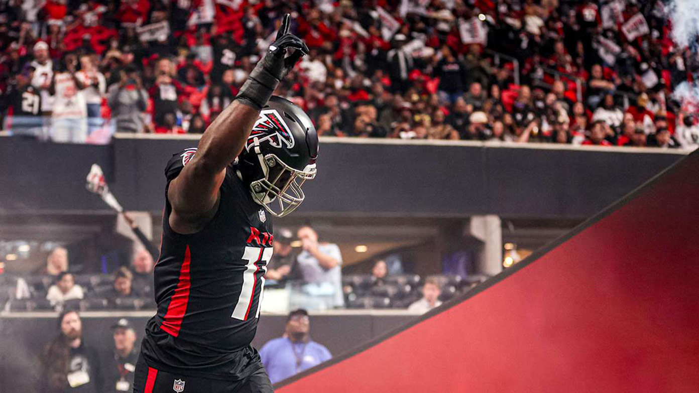 Jalon Walker lifts an arm in a celebratory gesture as he takes the field with the crowd behind him.