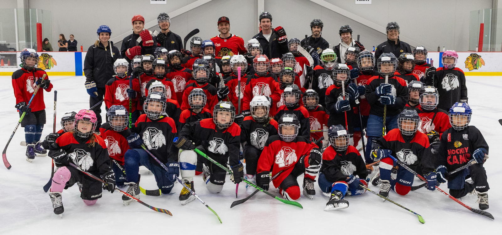 Young hockey players and adults pose on an ice rink.