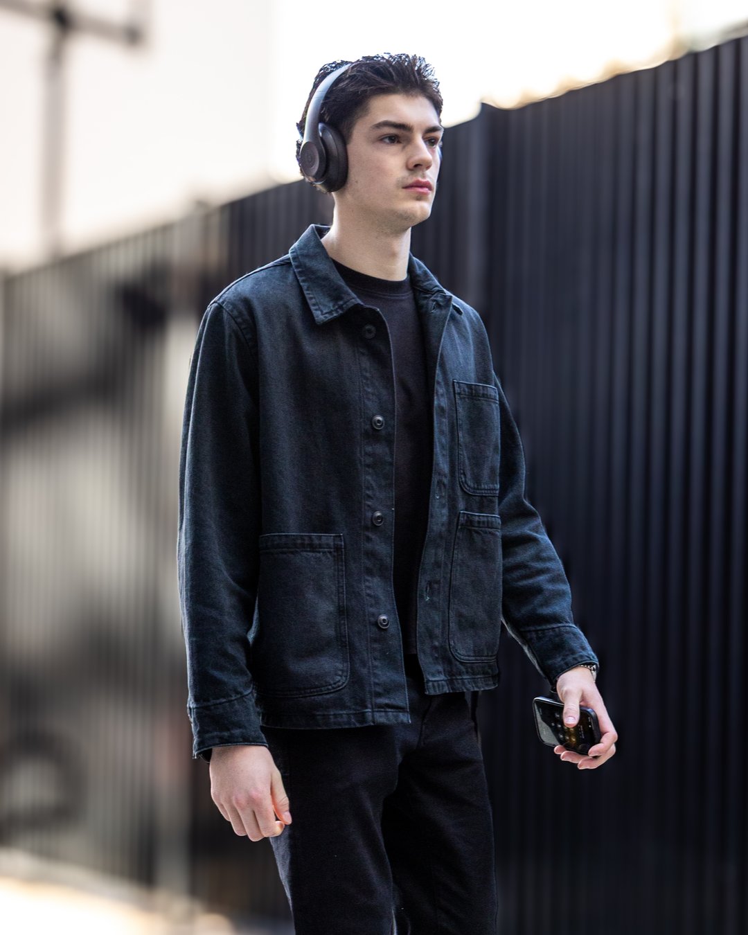 Person with headphones and smartphone walking outdoors.