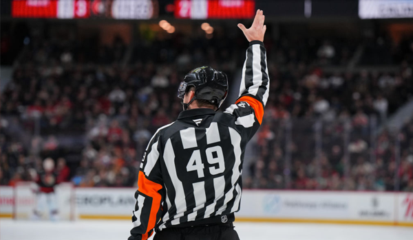 NHL referee raises his arm to call a penalty on the ice