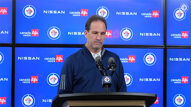 Scott Arniel speaking into a microphone in front of reporters