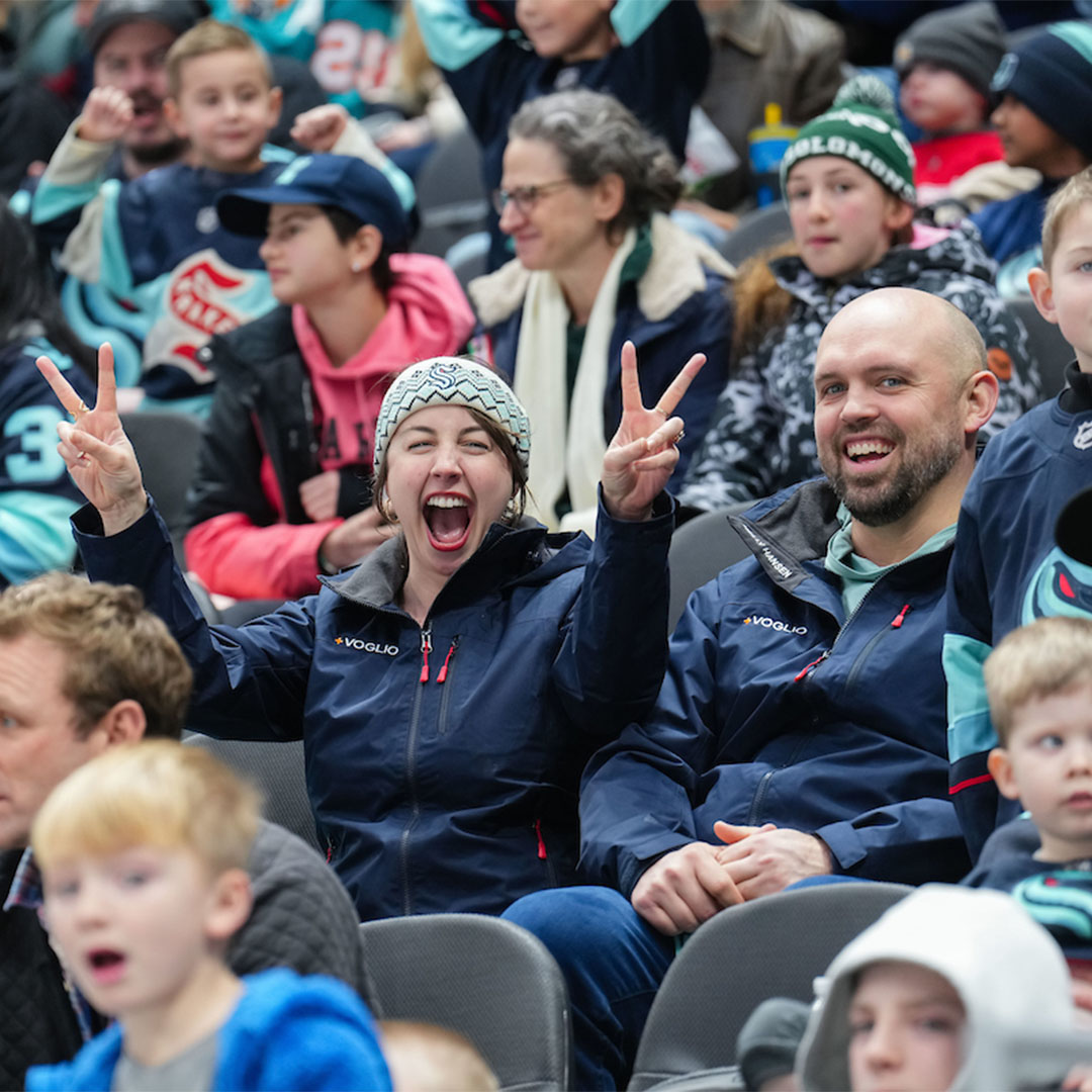 Photo of smiling fans in the crowd at a Kraken game