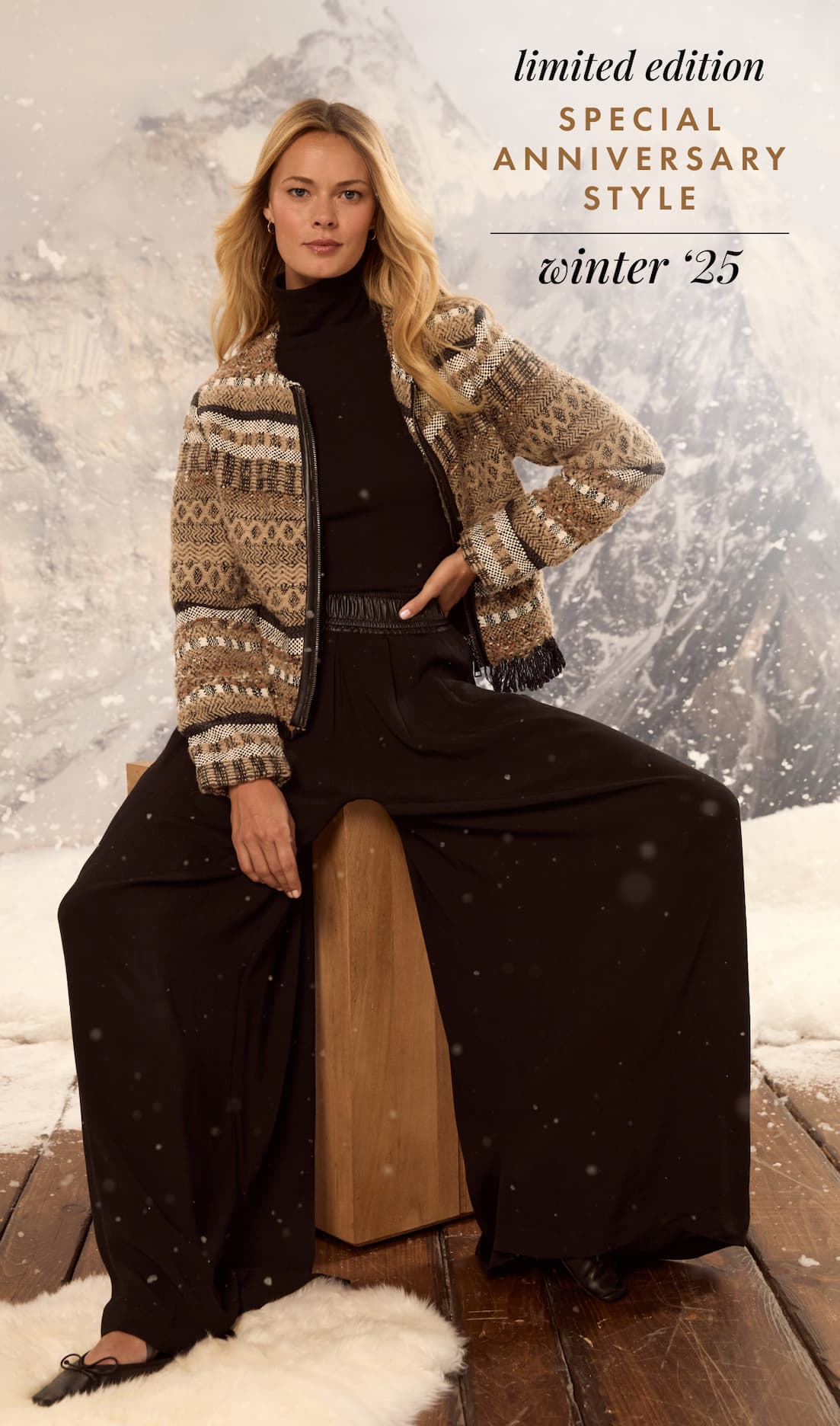 Woman wearing a black pants and a brown knit jacket sitting on a stool with a snowy background.