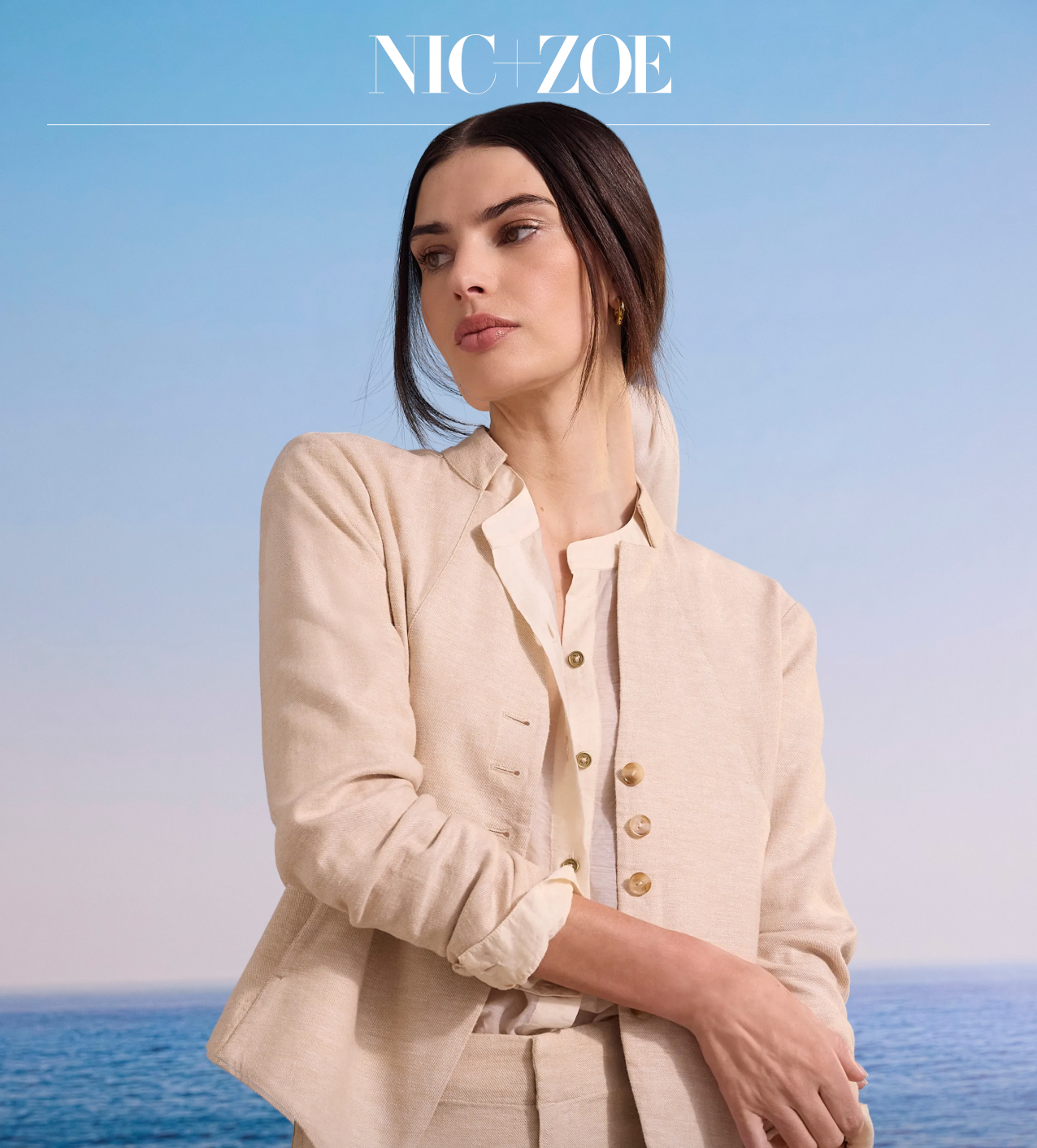 A woman posing in a cream-colored textured blazer layered over a button-up shirt and matching trousers, set against an ocean and blue sky background. Overlay text reads "LIGHT LAYERS." Wear in case of overactive A/C and chilly nights.