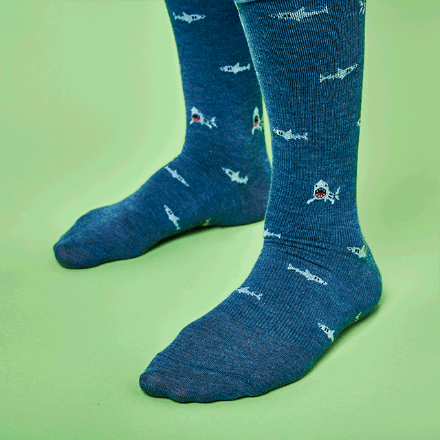 A gif of a man wearing the men's compression socks in grey with sharks and black with chili peppers. Shop men's nursing socks.