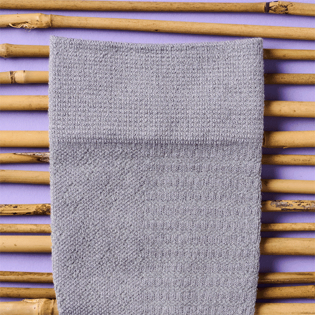Multiple bamboo compression socks in multiple colors laying against bamboo. Shop compression socks. 