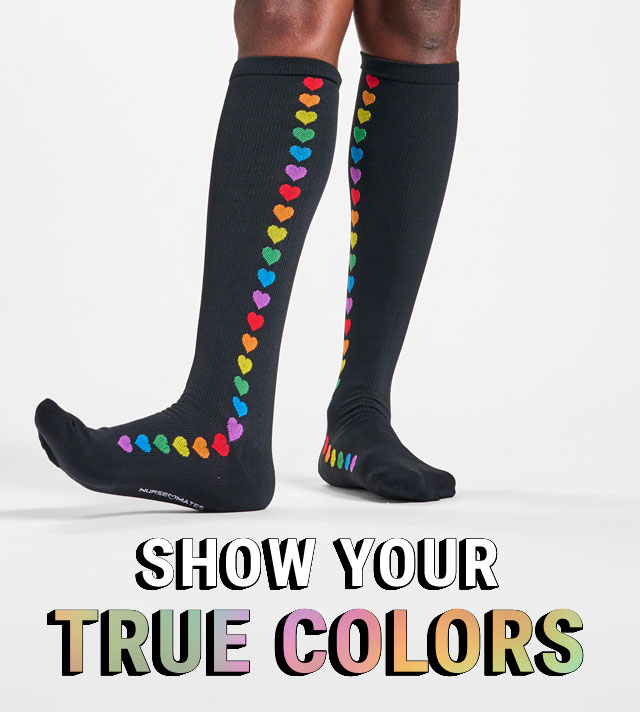 Show your true colors. A woman wearing rainbow compression socks in black rainbow hearts. Shop women's socks.