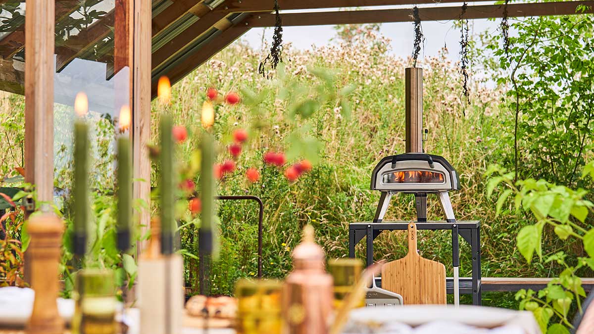 Ooni Karu 2 on and Ooni Table surrounded by an outdoor dinner set with candles and flowers