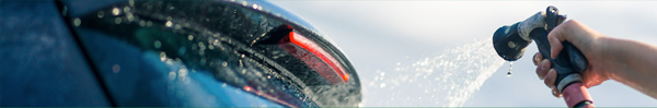 Spraying the rear of a car with a water hose