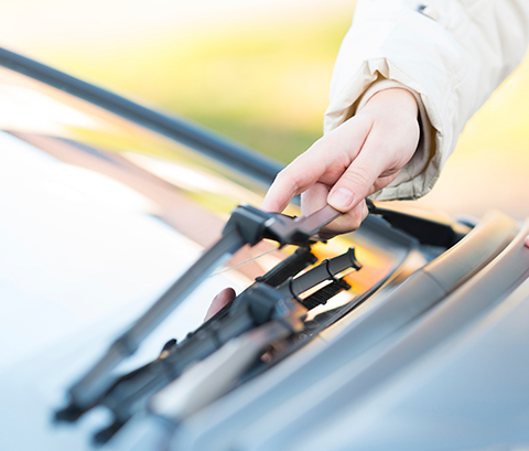 A hand resting on one of a vehicle's wiper blades.