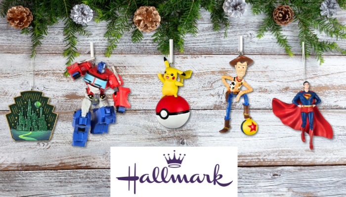 Assorted Hallmark Christmas ornaments including the Emerald City, Optimus Prime, Pikachu, Woody, and Superman hanging on a festive evergreen background with pinecones and the Hallmark logo below.