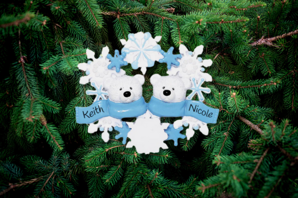 Two polar bears bundled in a blue scarf with names “Keith” and “Nicole,” surrounded by snowflakes—a cozy winter couple ornament.