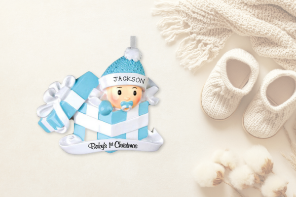 Baby boy in blue winter gear peeking from a striped gift box labeled “Jackson” with text “Baby’s 1st Christmas” below.