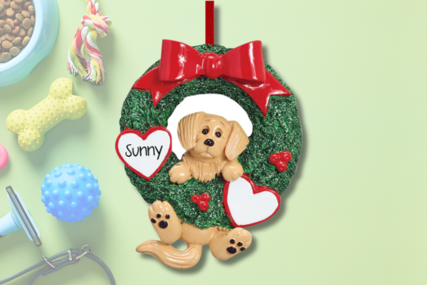 Personalized dog ornament with puppy inside wreath and pet name on heart.