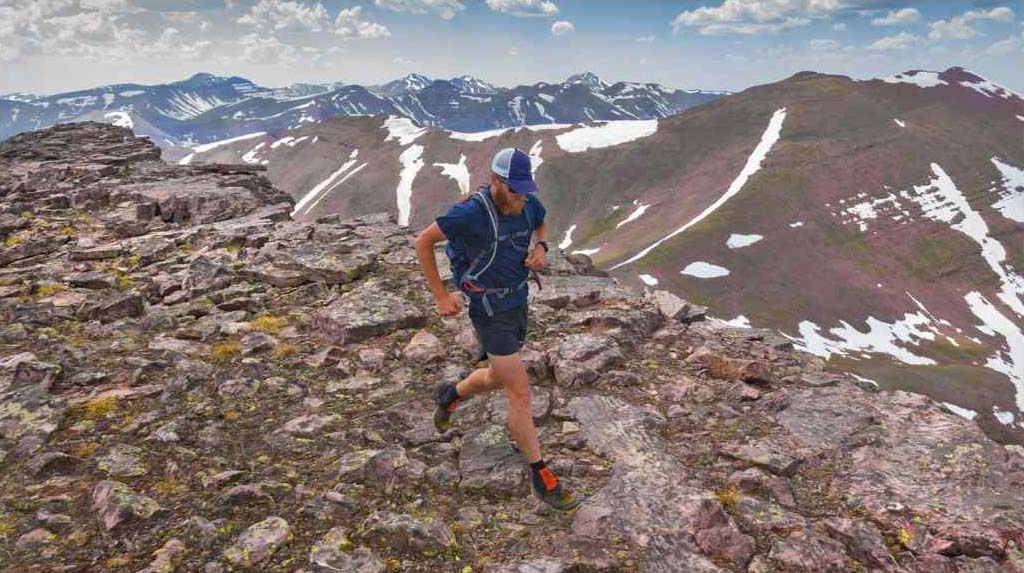 A person running on a rocky trail in the mountains.