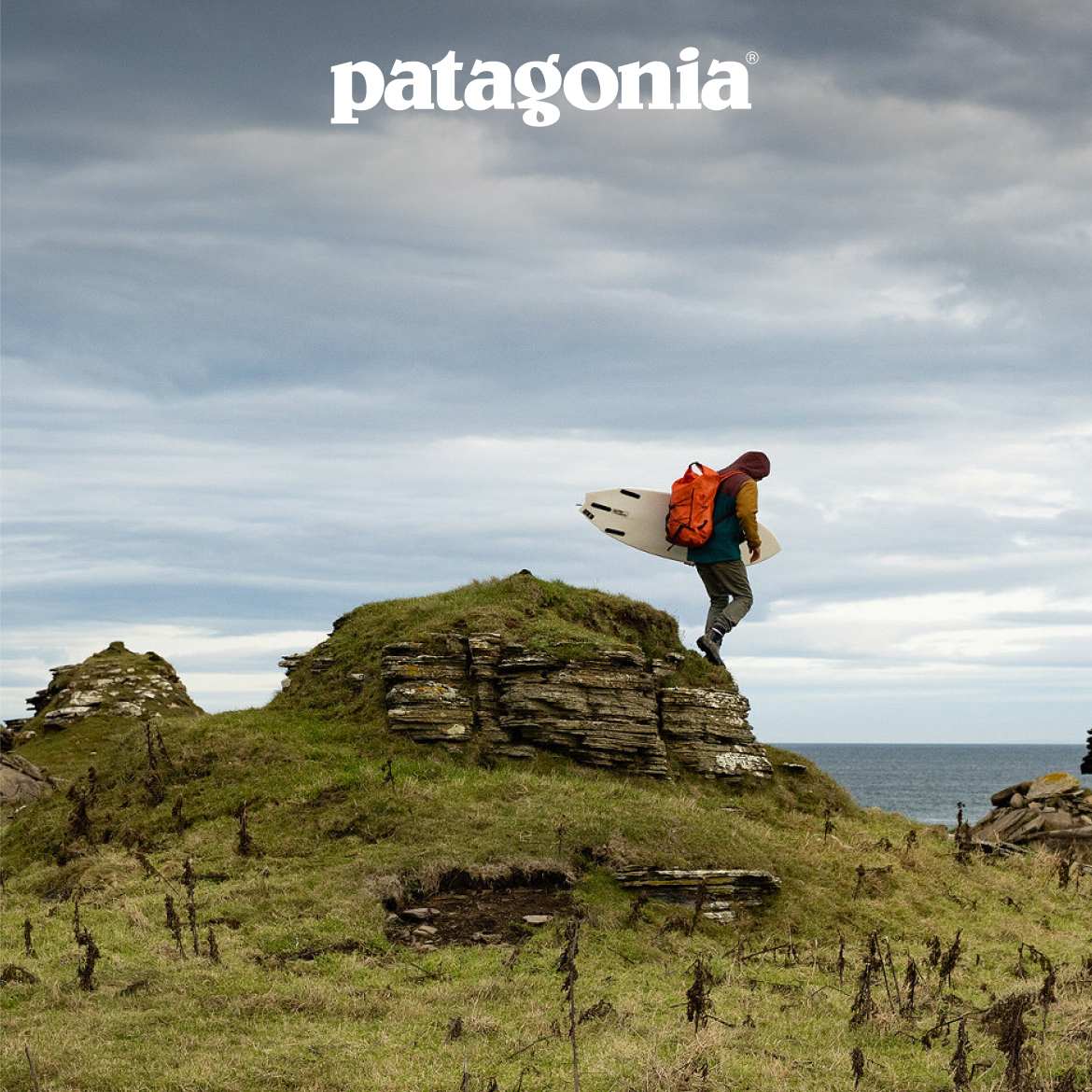 Patagonia. A surfer hikes toward the ocean with a backpack and a surfboard.