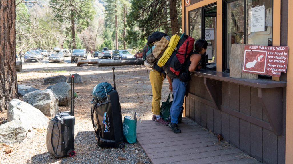 Two climbers stand at a ranger station in Yosemite with their luggage.