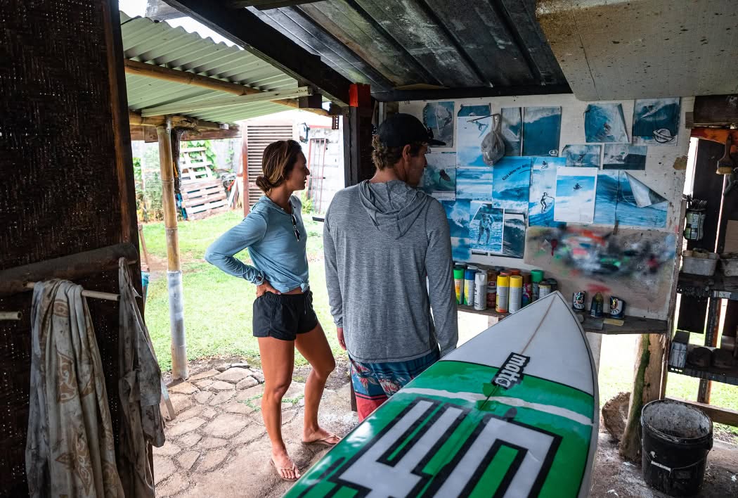 Two people look at photos on the wall of a surf shack.