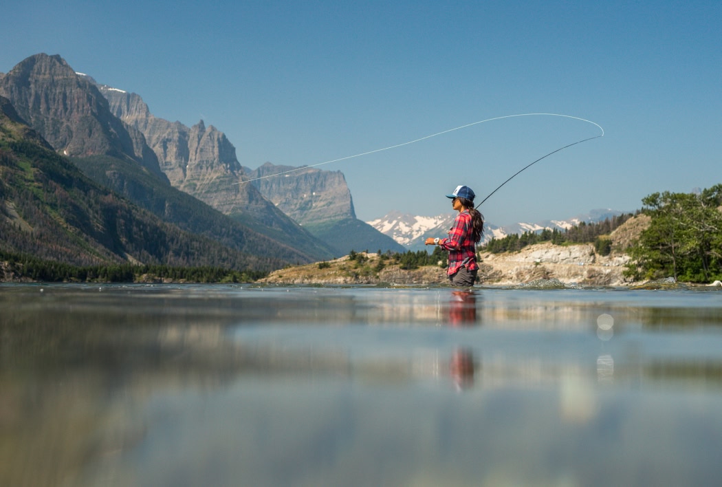 A person stands in a river casting a fly.