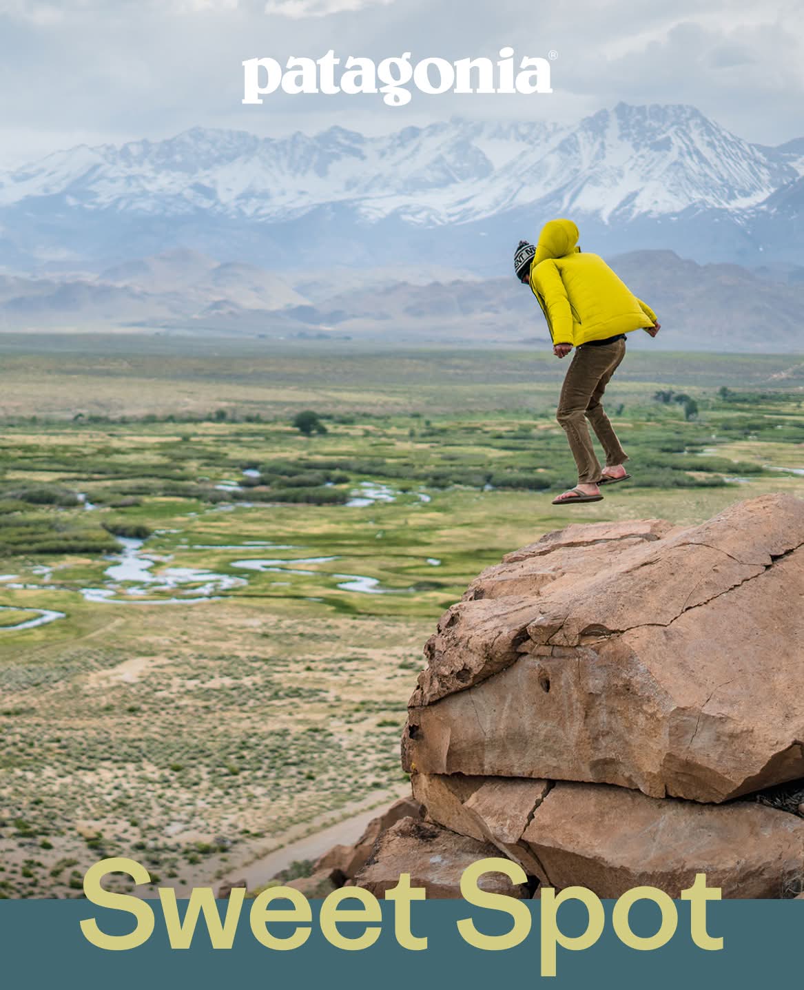 Patagonia. A person jumps on a rock overlooking a river on a windy day.