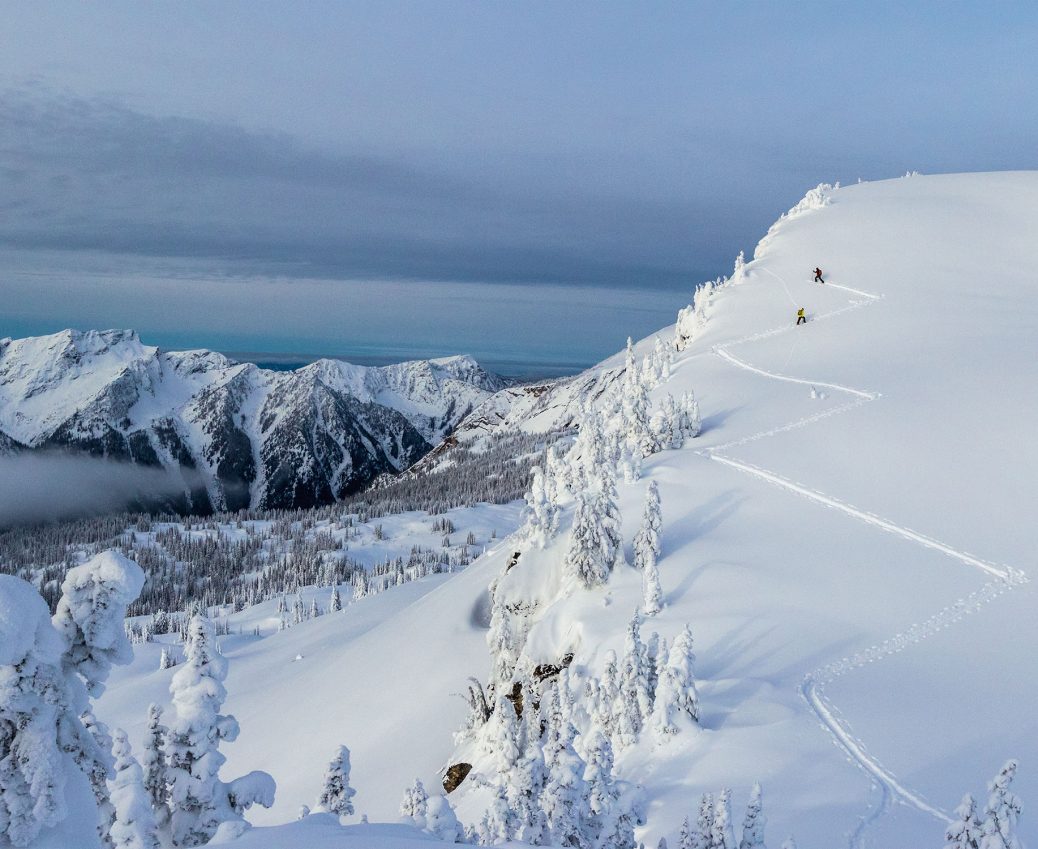 Photo of two people skinning up a snow-covered mountain.