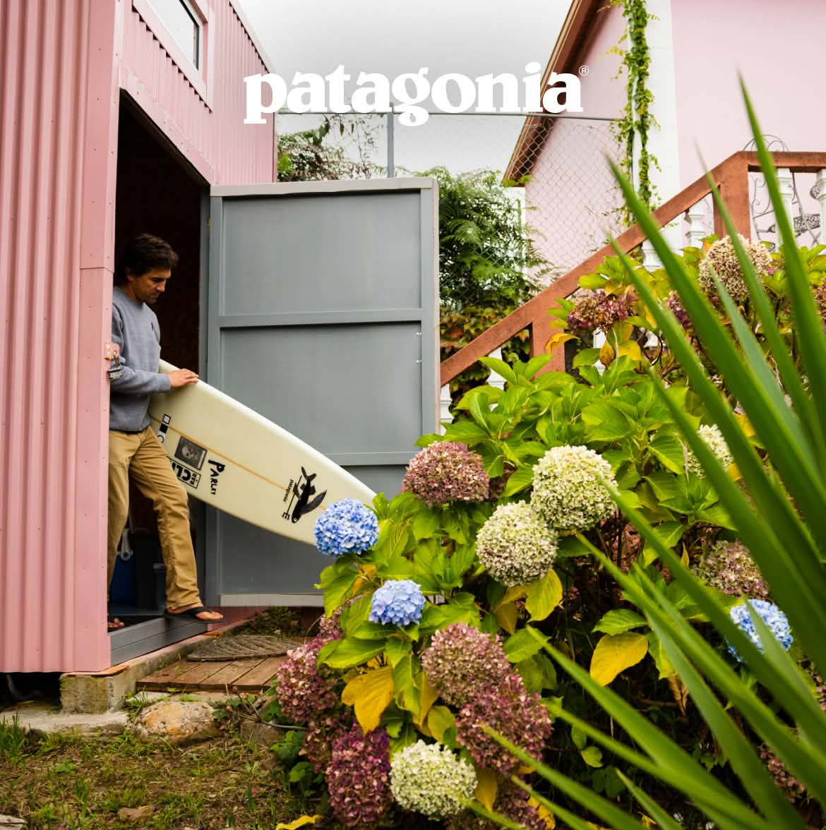 Patagonia. A person steps out of a building with a surfboard.