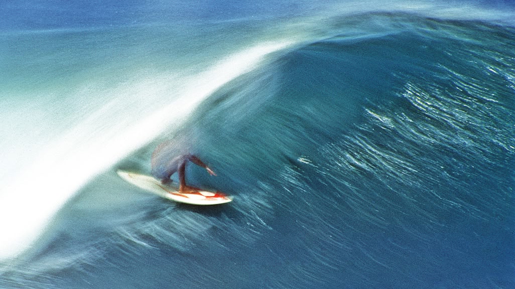 A surfer gets barreled by a wave.